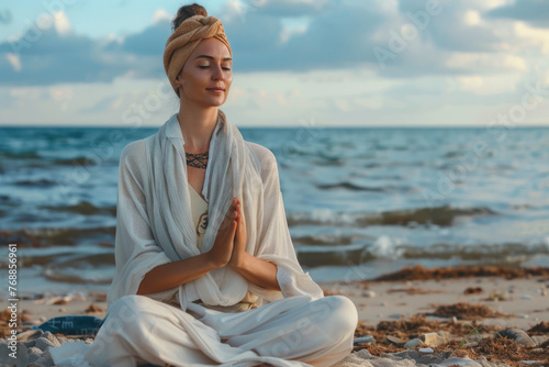 Beautiful young woman sitting on the beach mediating photo