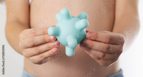 The girl holds a model of the virus against the background of her stomach. Concept of viral intestinal infections in children. Rotovirus infection, close-up photo
