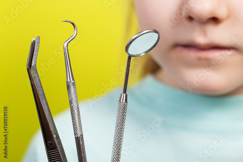Dental instruments against the background of the mouth of a seven-year-old girl. Surgical dentistry concept, removal of baby teeth and treatment of caries, close-up