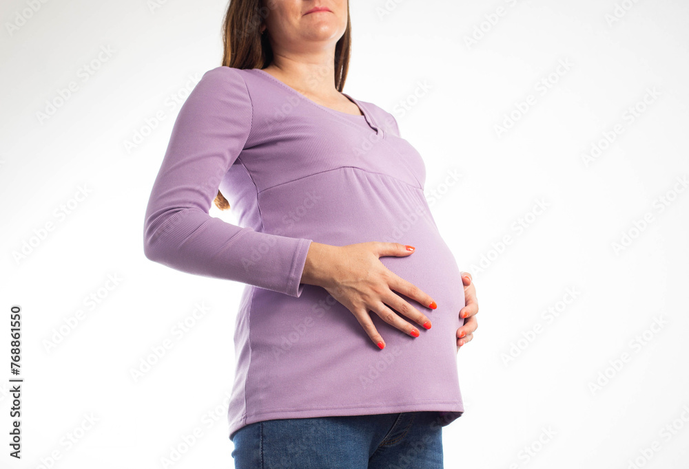 A pregnant girl in a purple sweater holds her stomach with her hands in
