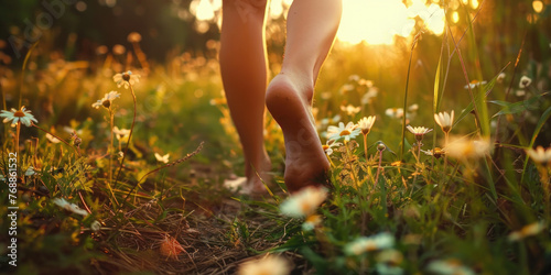 Woman walking barefoot outdoors in a field full of wild flowers, grounding concept.