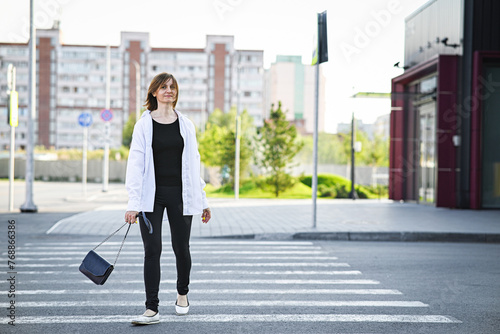 Young woman in formal clothes walking near grey wall outdoors, space for text © Svetlana