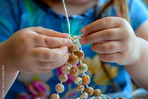 child threading wooden beads onto a yarn necklace photo