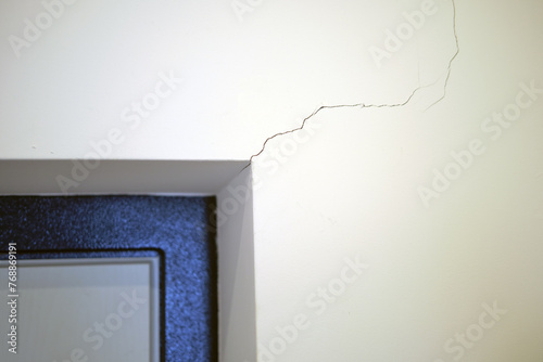 Cracked walls indoor a house in an apartment, white wall with a crack