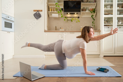 Pregnant woman does yoga at home and does exercises in the bird dog pose, exercises to prepare for childbirth