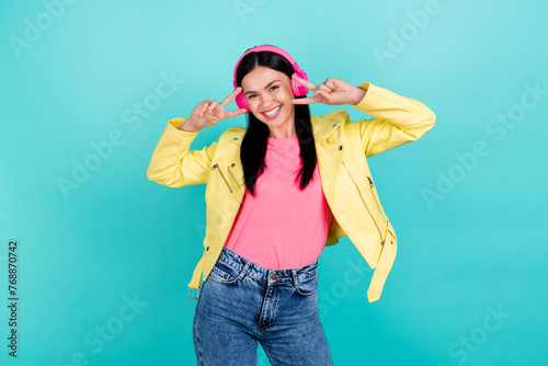 Photo of cheerful lady have fun show peace cool v-symbol enjoy music earphones isolated over teal color background