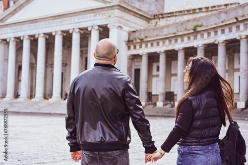 Back view of Happy smiling beautiful  Tourists  couple traveling at  Naples Italy,  in front of  Piazza del Plebiscito , Italy.Concept of Italian gastronomy and travel. Italian couple 