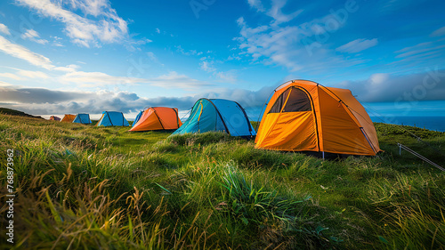 Vibrant camping tents cluster on lush grass against blue sky