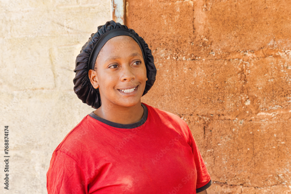 single african young woman with headwear standing in front of the house in a village, single african young woman with headwear standing in front of the house in a village,