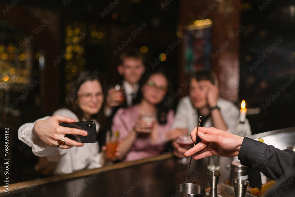 Bartender makes beverages for happy guests at counter focus on hands. Happy atmosphere and relax with alcoholic drinks in funny company