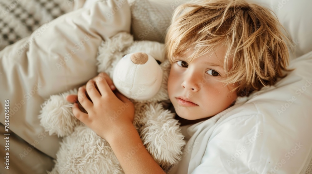 A young boy hugging a white teddy bear tight, his blonde hair tousled on the pillow A young boy hugging a white teddy bear tight, his blonde hair tousled on the pillow