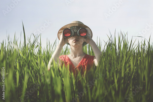 Fotografie surreal woman with spyglass hidden in the grass, abstract concept
