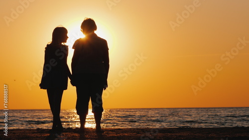An elderly woman stands next to her granddaughter at sunset. Active seniors
