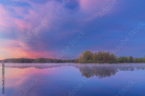 Foggy spring landscape at dawn of the shoreline of Whitford Lake with mirrored reflections in calm water, Fort Custer State Park, Michigan, USA © Dean Pennala