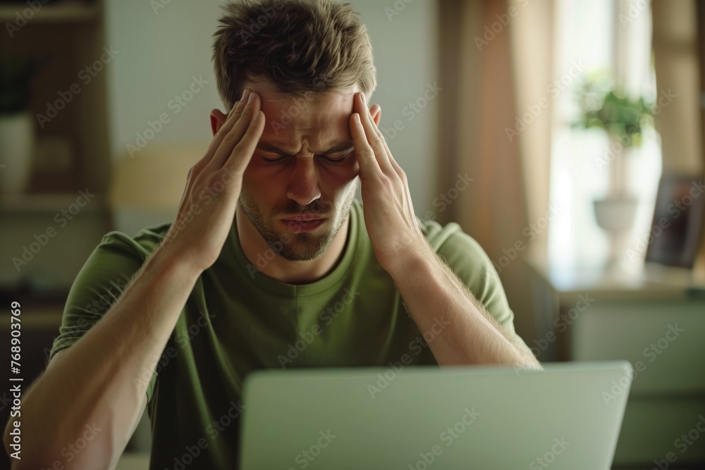 Young man experiencing a headache while working on the computer.
Young man experiencing a headache while working on the computer.
