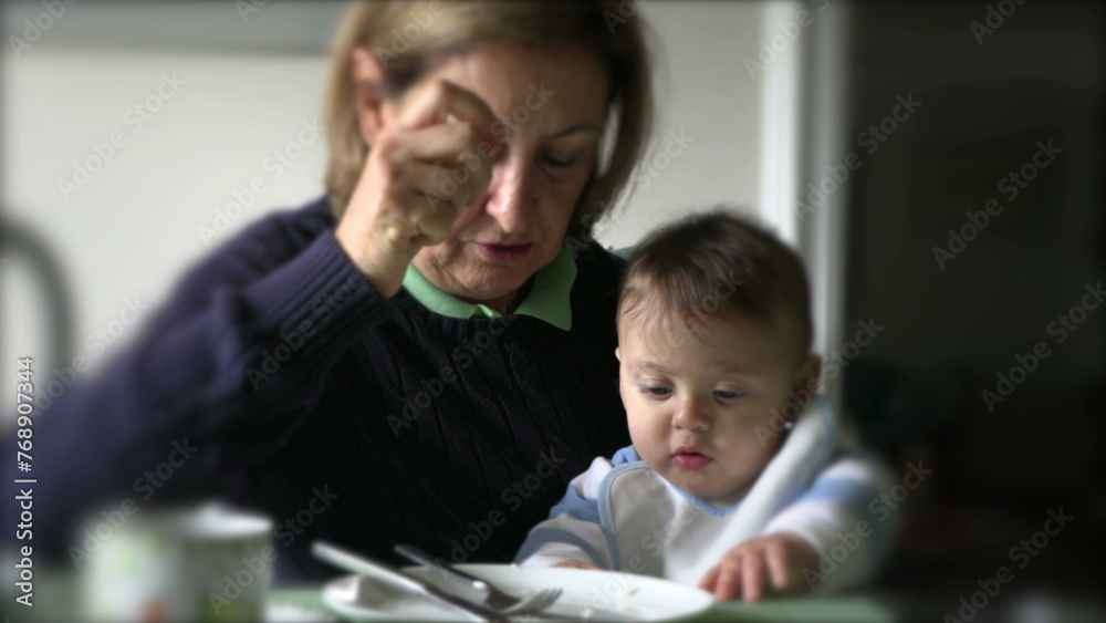 Obraz premium Grand-mother with grand-son baby toddler at meal table