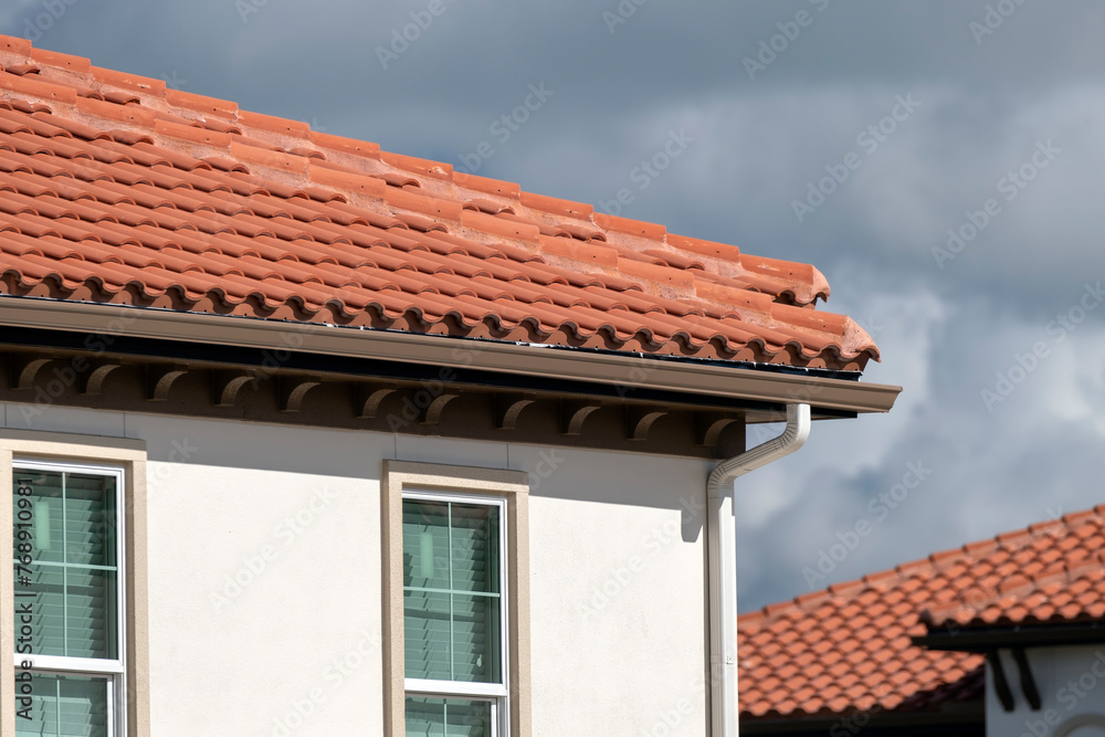 Tiled roof covering of condo building in Florida. Closeup of house rooftop covered with ceramic shingles Tiled roof covering of condo building in Florida. Closeup of house rooftop covered with ceramic shingles