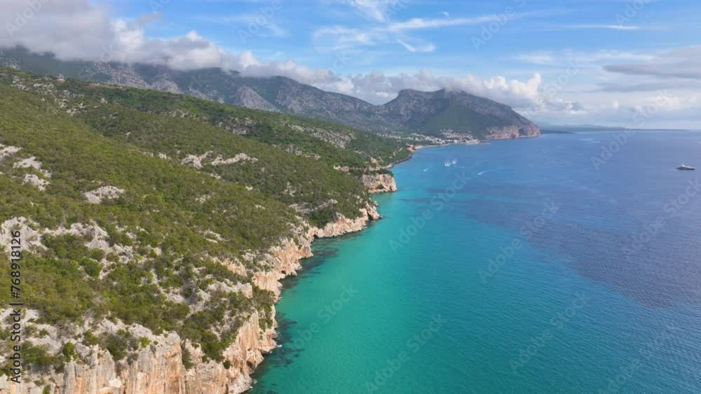 Aerial - Panoramic view of rocky coastline of Sardinia, with mountains rising up in the mainland of the island Aerial - Panoramic view of rocky coastline of Sardinia, with mountains rising up in the mainland of the island