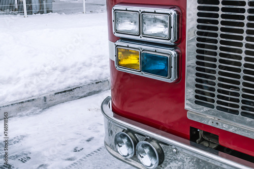 AThe rescue service. The cabin of the fire truck. Multi colored headlights of a fire truck. Chrome bumper and radiator grille of the fire truck. The signal of the fire truck.