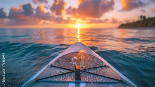 A paddleboard and paddle on a calm beach with the sunrise photo