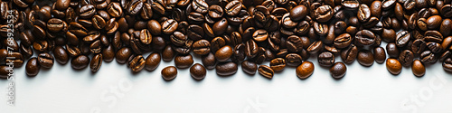 A close up of coffee beans on a white background. The beans are spread out and appear to be of different sizes