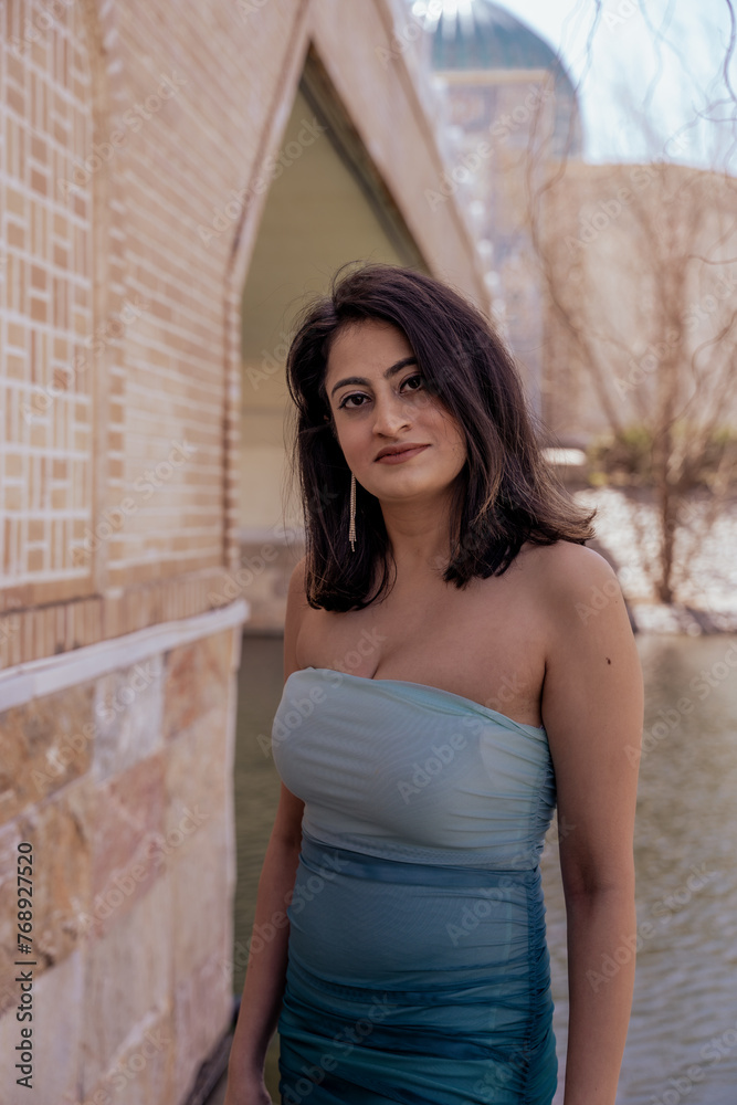 Fototapeta premium A woman in a blue and white dress stands in front of a brick wall