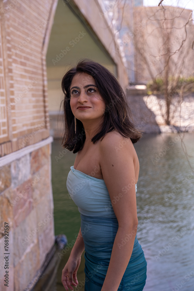 Obraz premium A woman in a blue dress stands in front of a brick wall