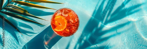 A glass of orange juice with ice cubes in it is sitting on a table next to a pal photo