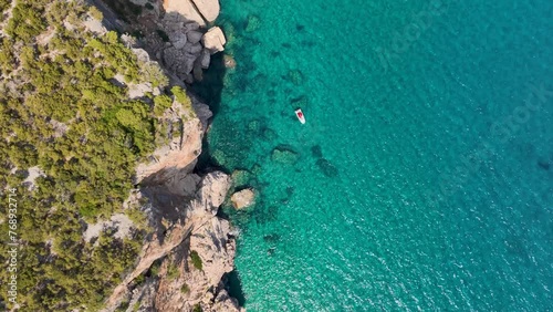 Directly bellow - Steep cliffs on Sardinian coastline and  turquoise blue water in the sea photo