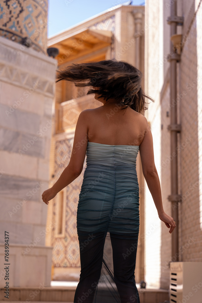 Fototapeta premium A woman in a blue and white dress is walking down a street