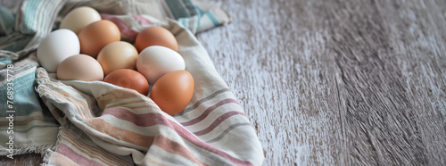 Fresh farm eggs on a linen cloth over a rustic wooden table. Farm and natural produce concept. Design for cookbook recipes, food blog headers with copy space, and organic product packaging. photo