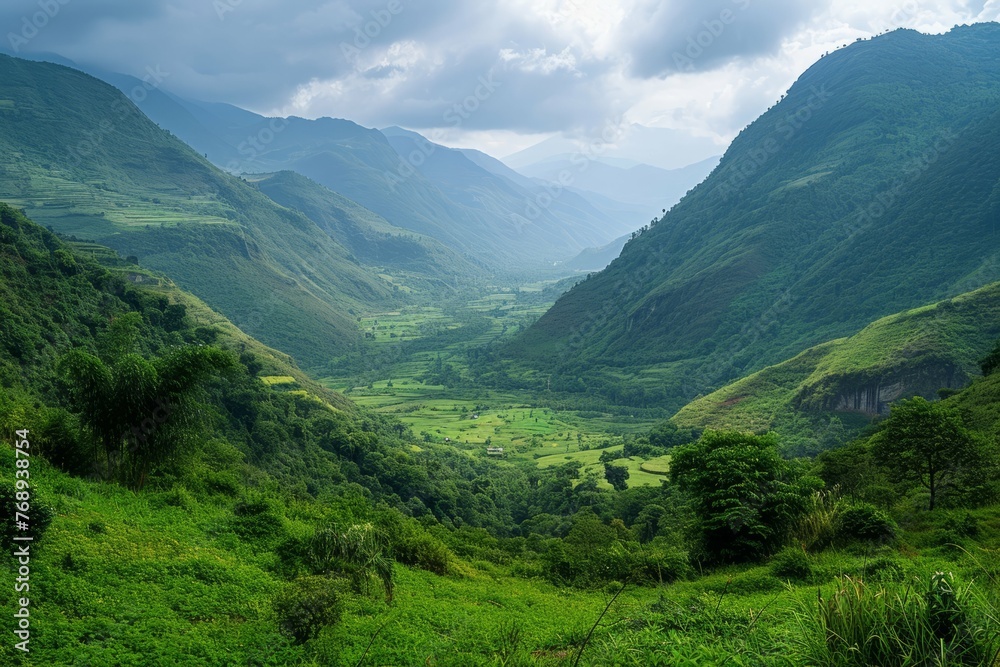 Fototapeta premium Lush green valley with rolling hills under a cloudy sky.