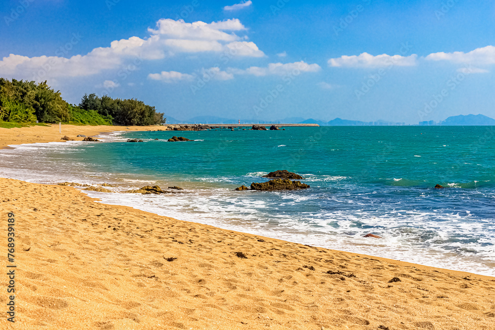 Obraz premium View of the shore of the South China Sea with a sandy beach and large rocks. Sanya, China.