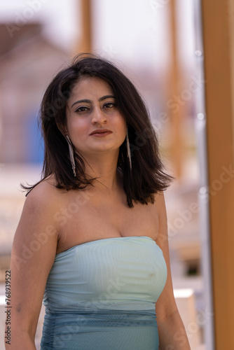 A woman in a blue and white dress stands in front of a brown pole Free Download A woman in a blue and white dress stands in front of a brown pole - GFXLoad