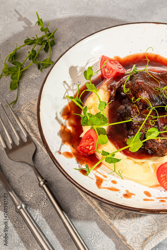 Mashed potatoes with beef in sweet and sour sauce, decorated with tomatoes and microgreens.