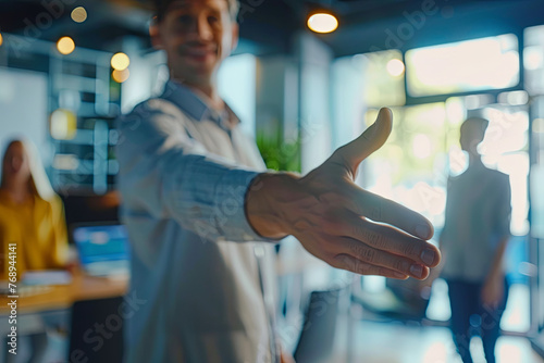 A welcoming business leader introducing a new team member into the firm, extending a handshake amidst a modern workspace with team members visible behind