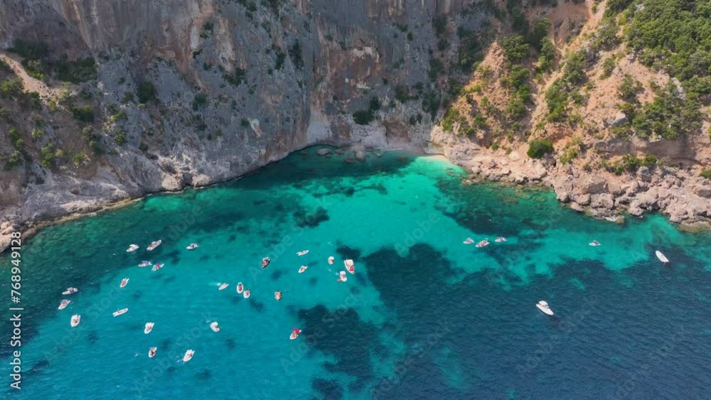 Aerial shot - Bay with turquoise water full of small tourist boats visiting the hidden beaches of Sardinia Aerial shot - Bay with turquoise water full of small tourist boats visiting the hidden beaches of Sardinia
