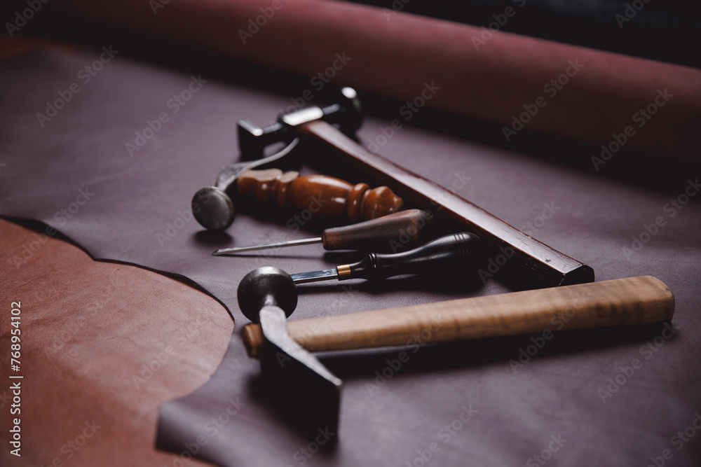 Fototapeta premium Equipment of Tailor for making shoe on background different rolls natural brown leather. Banner shoemaker industry, craftsman of workshop for skin