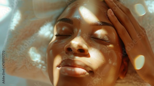 Woman  relax and massage on face with hands and care for facial  wellness and spa treatment on bed. Above  lens flare and african female person with skincare and cosmetics at hotel with skin glow.