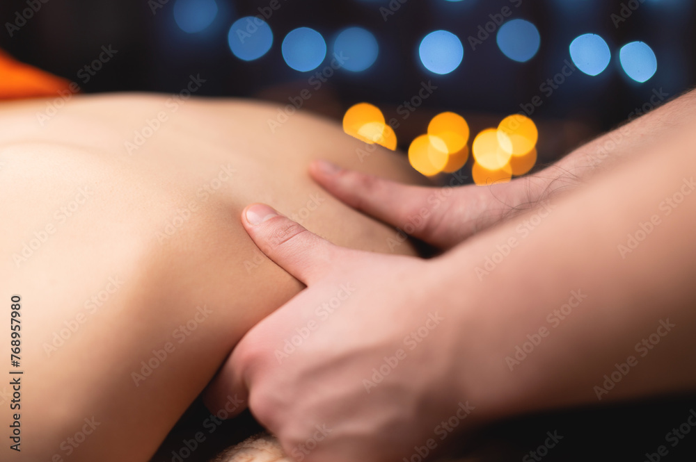 Male hands giving a trapezius muscle massage to a young girl in a professional massage room. - obrazy, fototapety, plakaty 