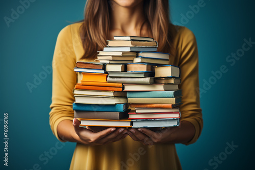 hands holding a large stack of books close-up