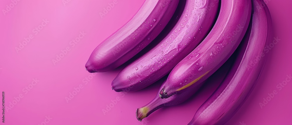   Purple bananas sit atop pink surface with droplets of water