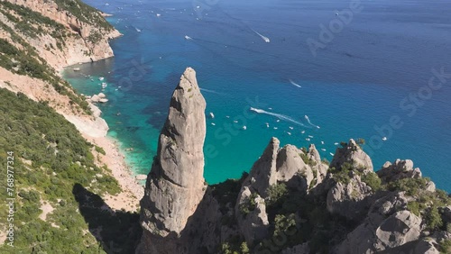 Aerial - Drone flying past a huge rock formation at Cala Goloritze on the Sardinian coast with deep blue sea down bellow