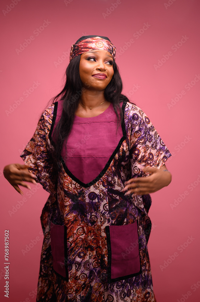 Joyful African Woman dancing and happy over a successful transaction in Pink Ankara isolated on pink background. Studio portrait. Lady lifestyle concept Joyful African Woman dancing and happy over a successful transaction in Pink Ankara isolated on pink background. Studio portrait. Lady lifestyle concept