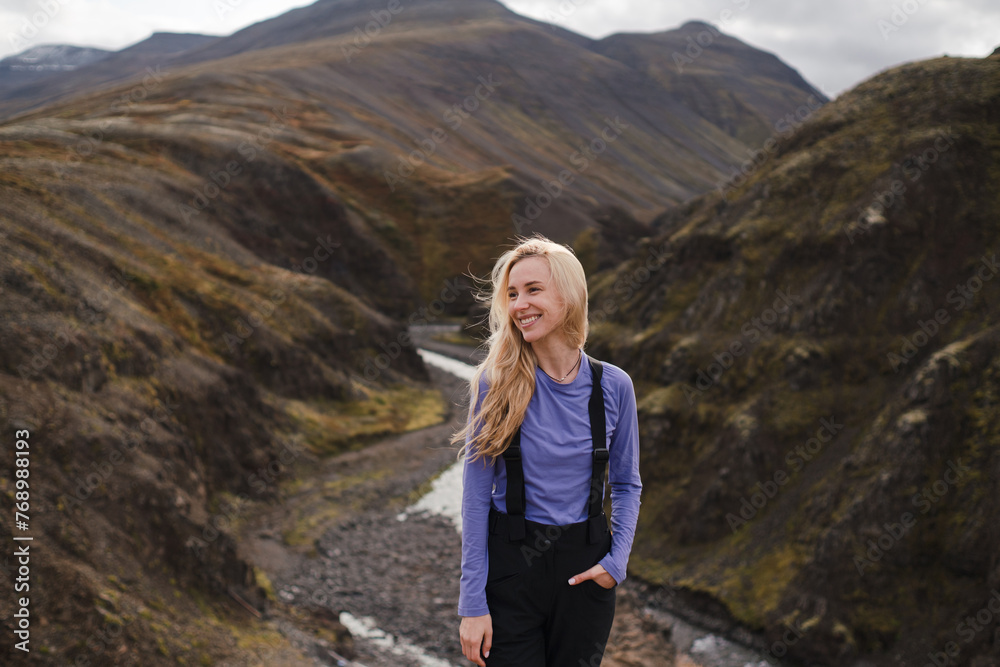 Traveling and exploring Iceland landscapes and travel destinations. Young female tourist enjoying the view and outdoor spectacular scenery. Summer tourism by Atlantic ocean and mountains.