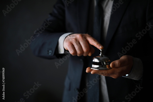 Portrait of Businessman in Black Suit Holding silver Bell. Ring for Service Concept.