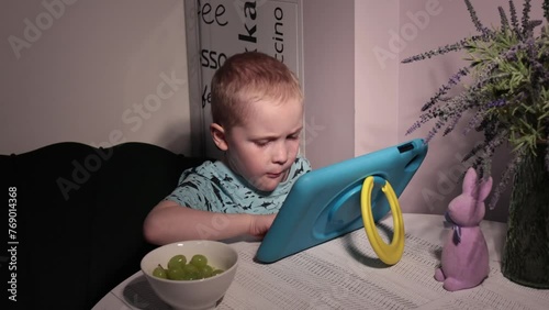 Little cute boy gets a bowl of fresh grapes and eats them