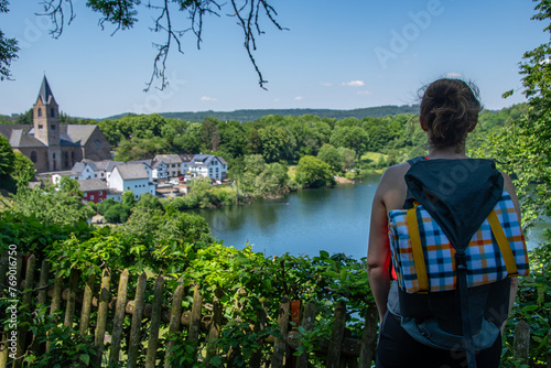 A hiker with a backpack enjoys the view of the Ulmener Maar