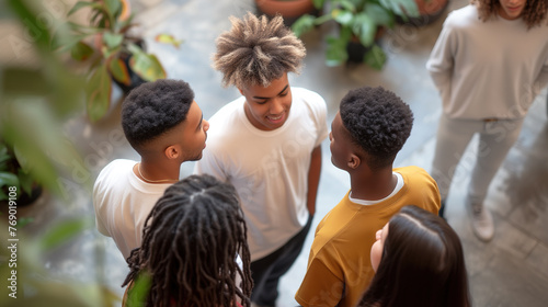 Group of smiling mixed-race young people talking, with one guy standing alone aside. Multicultural friends or students having a conversation. Diversity concept. photo