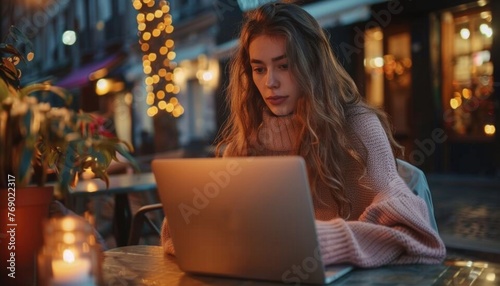 Woman working on laptop at evening cafe